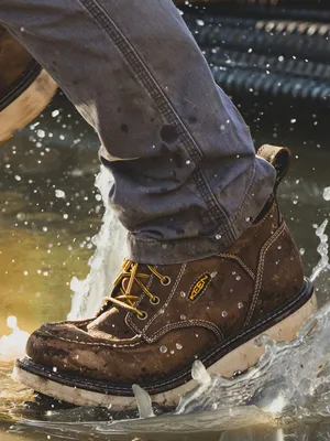 A waterproof work boot splashing through water